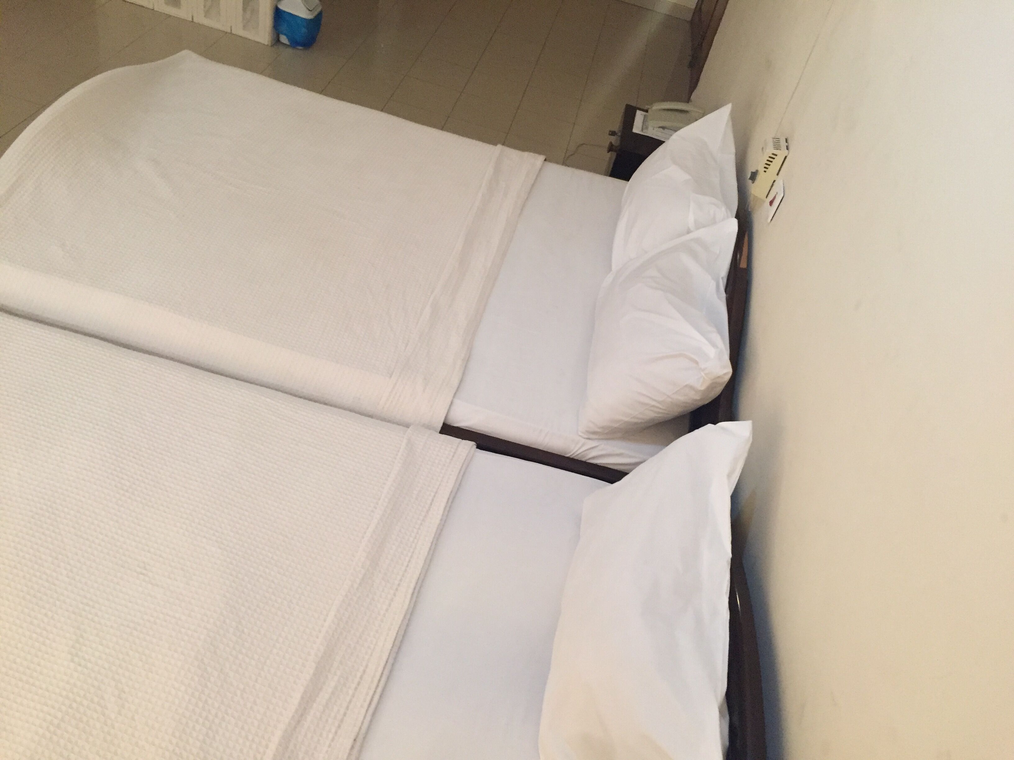 Una cama doble con sábanas blancas en una habitación de hotel.