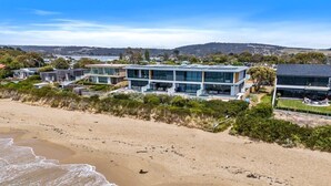 Une propriété située en bord de mer, dotée d’une architecture moderne, notamment d’un immeuble à plusieurs étages avec de grandes fenêtres et un toit plat.