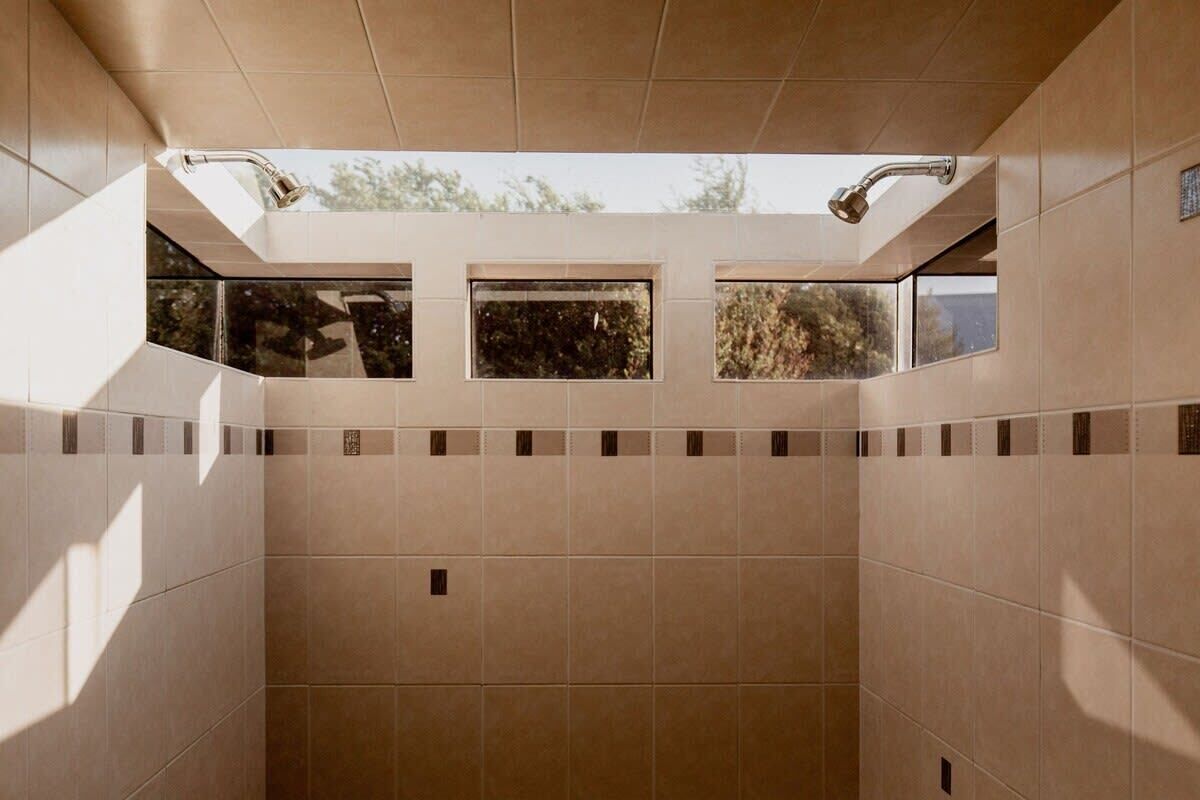 A modern bathroom with large windows, a shower area, and a tiled floor.