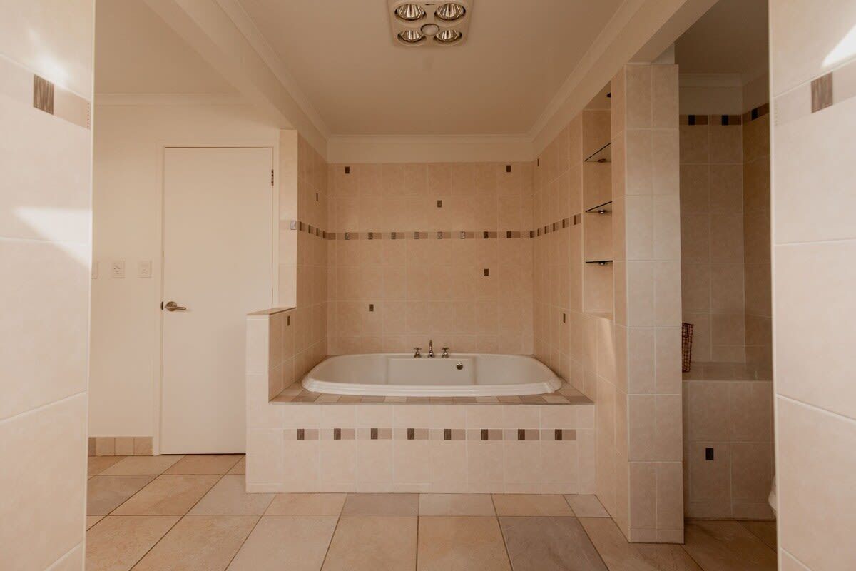A modern bathroom with a freestanding bathtub, tiled walls, and a door leading to another room.