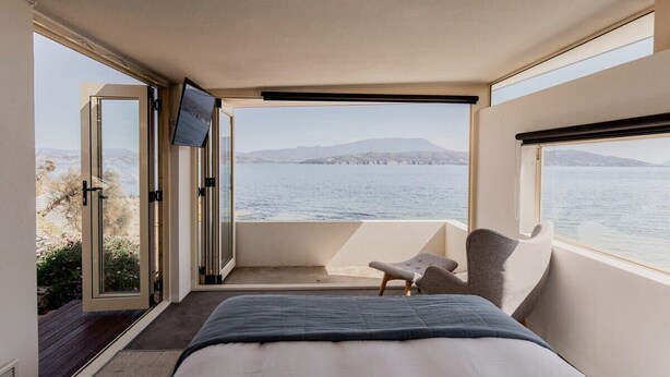 Une chambre avec un lit, une télévision et une vue sur la mer.