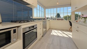 Une cuisine moderne dotée d’une grande fenêtre, d’un four encastré et offrant une vue sur la ville.