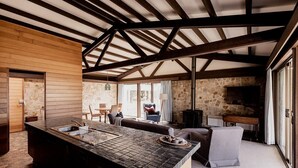 A spacious kitchen with a large island, stone walls, and a vaulted ceiling. - Waterfront Boltons Beach Cottages - room for 8 (Triabunna)