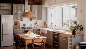 Una cocina moderna con zona de comedor, que cuenta con un amplio ventanal, armarios de madera y una isla central.