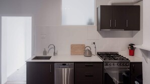 Een moderne keuken met een vaatwasser, fornuis, oven en donkere kastjes.