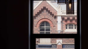 A window with a view of a brick building, including a shop with a sign that reads "PRODUKT". - 3 Bedroom, Spacious Inner-City Pad (Hobart)