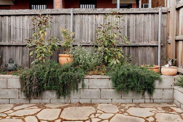 A stone patio with a rustic wooden fence and various potted plants.