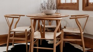 A dining area with a round wooden table, four wooden chairs, and a black and white cowhide rug.