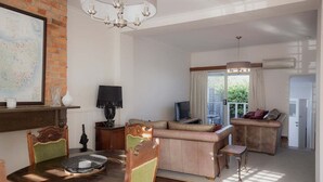 A dining area with a wooden table and chairs, a map on the wall, and a living area with a sofa and TV. - Mr Watson's Cottage in Battery Point (Battery Point)