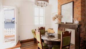 A dining area with a brick wall, a chandelier, and a map on the wall. - Mr Watson's Cottage in Battery Point (Battery Point)