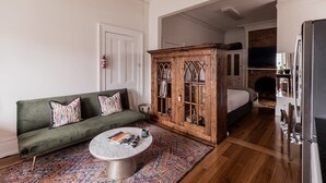 A living room with a green sofa, a coffee table, and a wooden cabinet with glass doors. - Central Hobart Studio (Hobart)