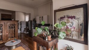 A spacious living room with a wooden coffee table, a large mirror, and a kitchen in the background. - Central Hobart Studio (Hobart)