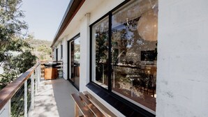 Un edificio moderno con amplios ventanales, una terraza de madera y vistas al paisaje circundante.