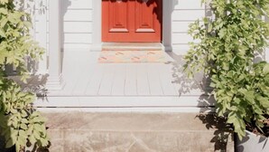 A white building with a red door, white trim, and a small porch with steps.