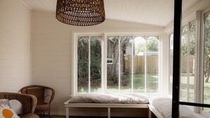 A cozy room with a large window, a wicker chair, a bench, and a bed. - Maple House - Charming family cottage in Sandy Bay (Sandy Bay)