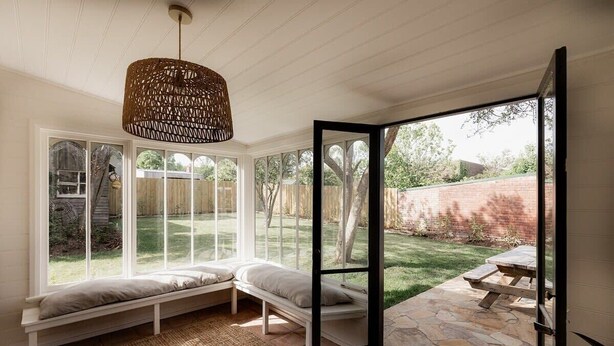 A room with a large window seat, a woven pendant light, and a stone patio area. - Maple House - Charming family cottage in Sandy Bay (Sandy Bay)