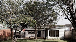 A residential property with a small house, a backyard with a lawn, and a tree. - Maple House - Charming family cottage in Sandy Bay (Sandy Bay)