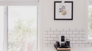 A modern kitchen with a white countertop, a coffee machine, and a framed artwork above it. - Modern refurbished unit in charming Bellerive (Bellerive)
