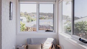 A cozy reading nook with a cushioned bench, a small side table, and a large window offering a view of the neighborhood. - Modern refurbished unit in charming Bellerive (Bellerive)