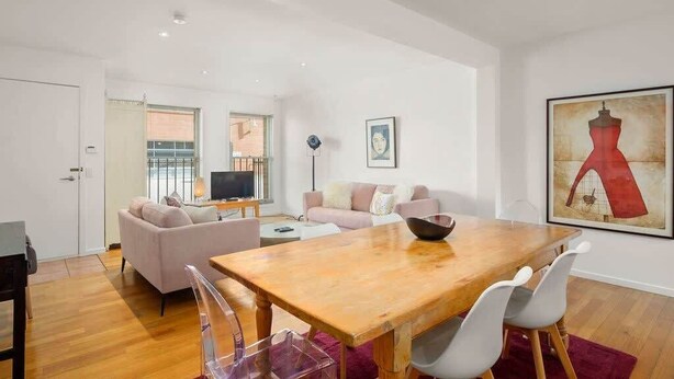 Un salon moderne avec une table à manger en bois, deux canapés et un téléviseur en arrière-plan.