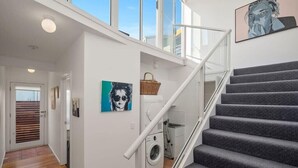 Un appartement moderne doté d’un escalier, d’un lave-linge et d’une grande fenêtre.
