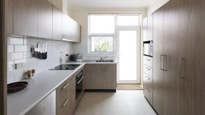 Une cuisine moderne avec des meubles de couleur bois clair, un évier en acier inoxydable et une fenêtre qui laisse entrer la lumière naturelle.