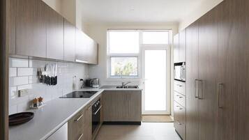 A modern kitchen with light wood cabinets, a stainless steel sink, and a window providing natural light.