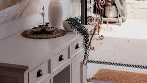 A room with a white console table, a large abstract painting, a lamp, and a view of an outdoor patio with a table and chairs. - Stay steps from Salamanca in historical cottage (Battery Point)