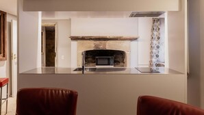 A modern kitchen with a built-in fireplace, a stainless steel countertop, and two leather chairs. - The Cellar Summary:<br>T (Hobart)