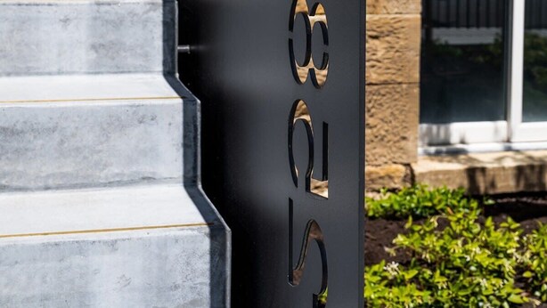A staircase with a black metal handrail and a door with a number "03" cutout. - The Cellar Summary:<br>T (Hobart)