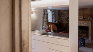 A kitchen with white cabinets, a sink, and a stone wall in the background. - The Cellar Summary:<br>T (Hobart)