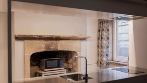 A modern kitchen with a built-in microwave, a stone fireplace, and a window with patterned curtains. - The Cellar Summary:<br>T (Hobart)
