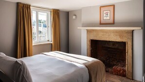 Een kamer met een bed, een open haard en een raam met gordijnen.