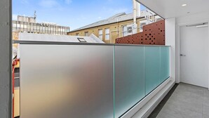 Un interno moderno con una parete divisoria in vetro, una porta e vista sugli edifici esterni.