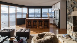 Eine moderne Küche mit einer Wand aus Stein, einer Bar mit Hockern und Blick auf einen See.