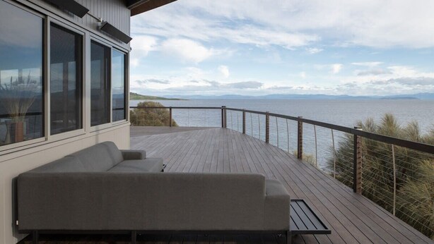Eine Terrasse mit einer Couch mit Blick auf ein Gewässer und entfernte Berge.