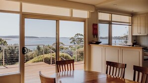 Un comedor con vistas al mar, una mesa de madera y sillas.