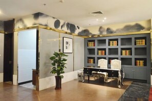 A room with a bookshelf, a desk, and a potted plant. - Guanhe International Hotel (Shijiazhuang)
