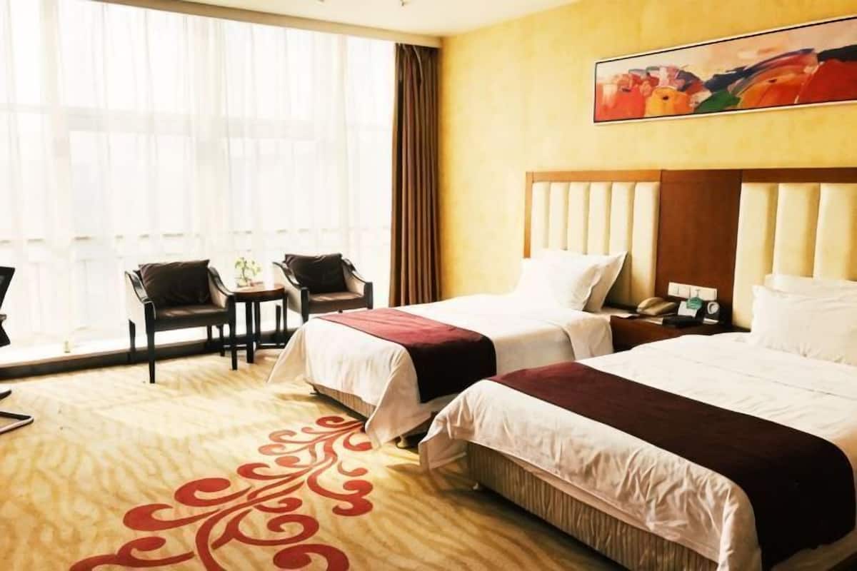 Ein Hotelzimmer mit zwei Betten, einem Schreibtisch, Stühlen und einem großen Fenster.