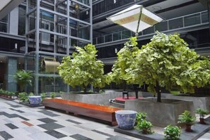A modern indoor space with large windows, potted plants, and a checkered floor pattern. - Guanhe International Hotel (Shijiazhuang)