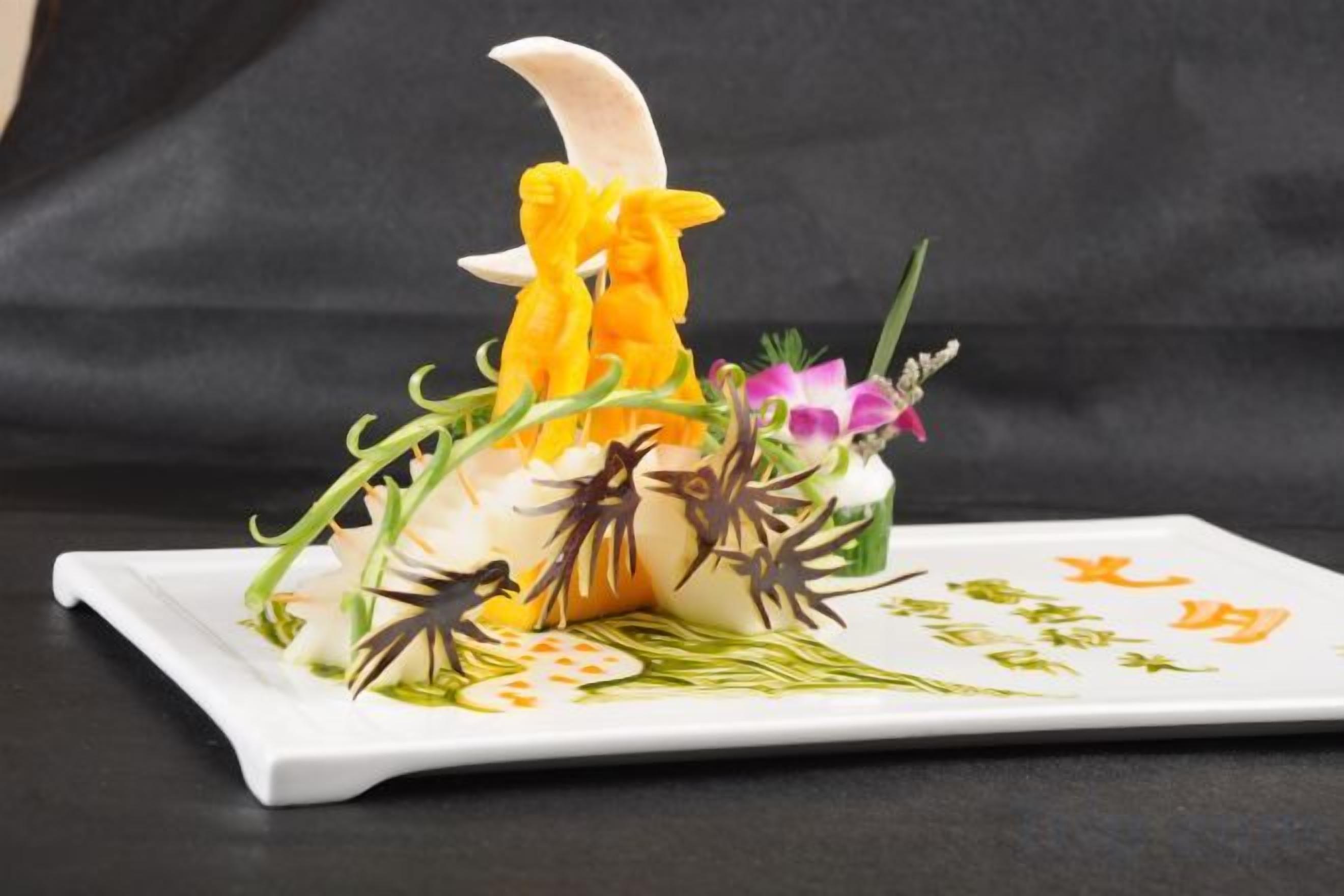 Une assiette blanche sur laquelle est présentée une composition culinaire, avec un plat principal au centre, entouré de garnitures colorées et de feuilles vertes.