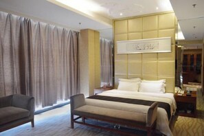 Una habitación de hotel con cama, una silla, una mesita de noche y un ventanal con cortinas.