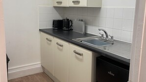 A compact kitchen with white cabinets, a black countertop, a sink, and a dishwasher. - Family Friendly One Bedroom Apartment w King Bed (Colchester)