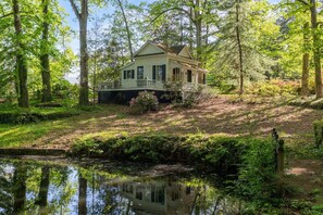 A house surrounded by lush greenery and a small pond. - Little White House Studio w/ Full Kitchen (Greensboro)
