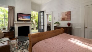 Un dormitorio con cama, televisor, chimenea y vistas al exterior.