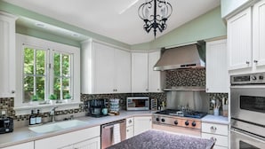 A modern kitchen with white cabinets, a granite countertop, a stainless steel stove, and a microwave. - The Cabin - Fire Pit, Pool Table, Spacious (Greensboro)