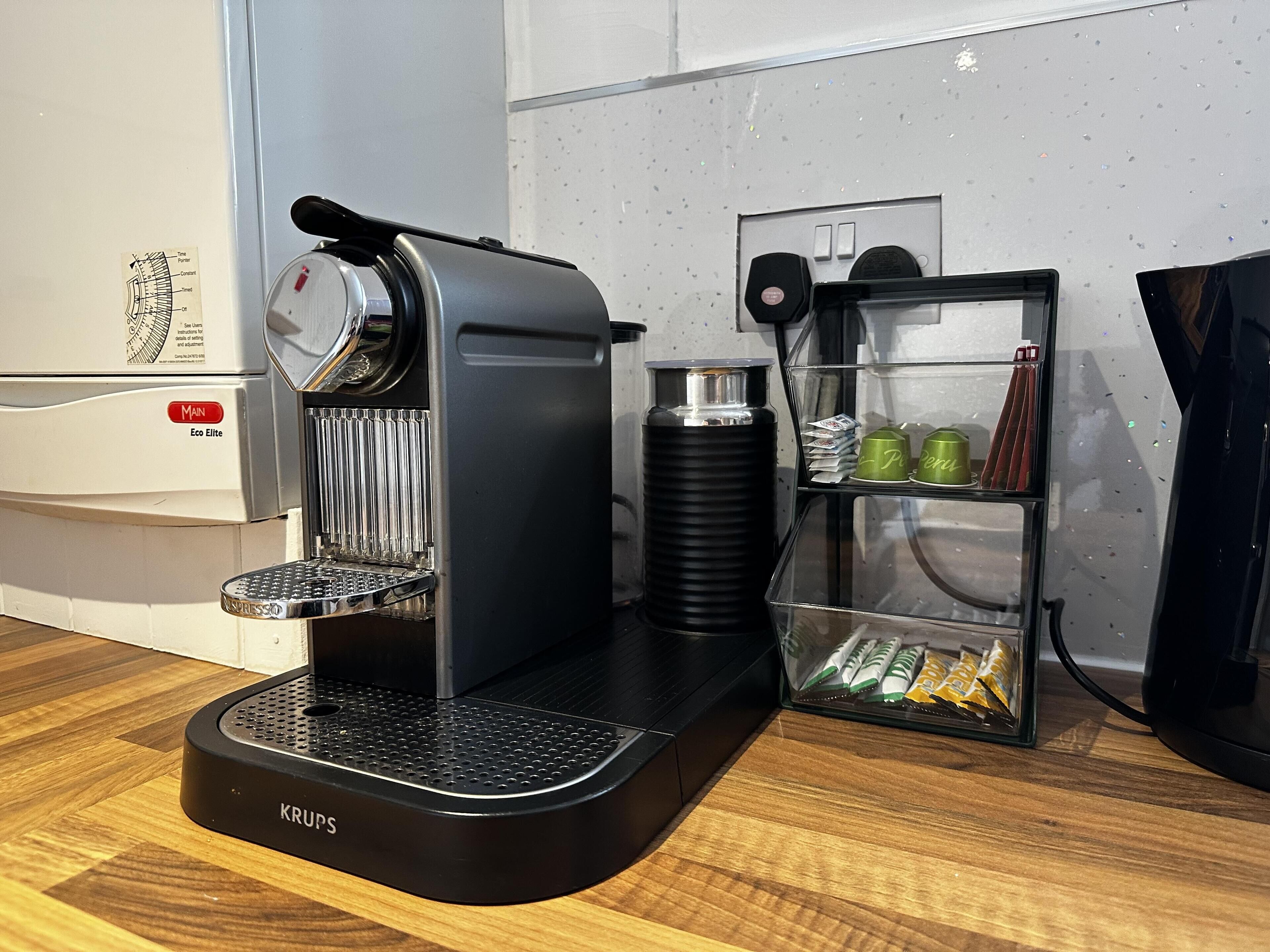 A Krups espresso machine with a coffee grinder, a water dispenser, and a coffee bean storage shelf.