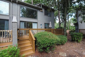 A modern building with a wooden deck, a seahorse decoration, and a well-maintained garden.