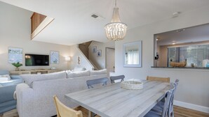 En moderne stue med sofa, spisebord og stole. Der er en trappe, som fører op til et øvre plan.