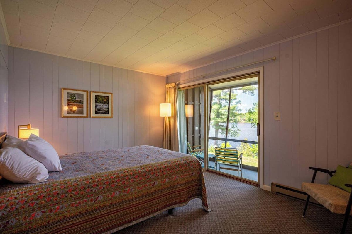 A bedroom with a bed, a chair, a window, and a door.